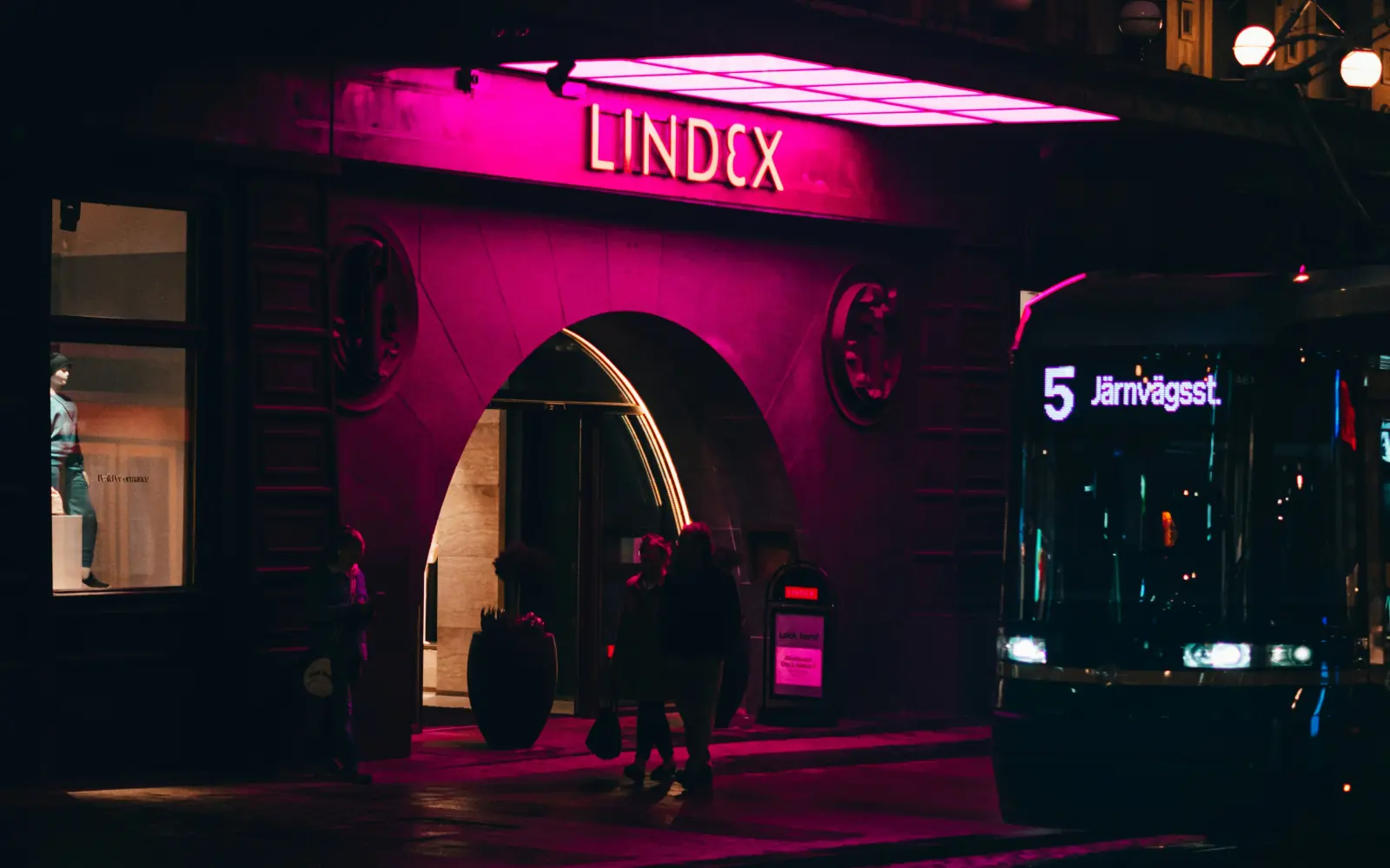 An evening shopping street in Helsinki: a store entrance and a tram
